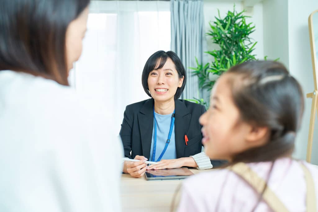親子とスーツ姿の女性の会話シーン