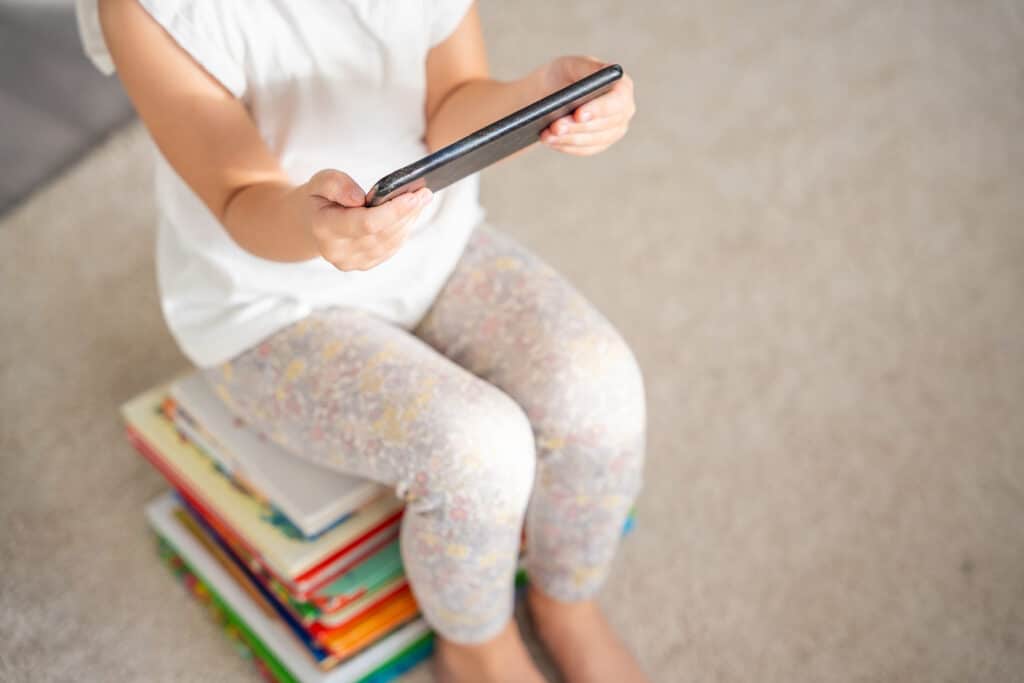 Child sits on a stack of children's fairy-tale books